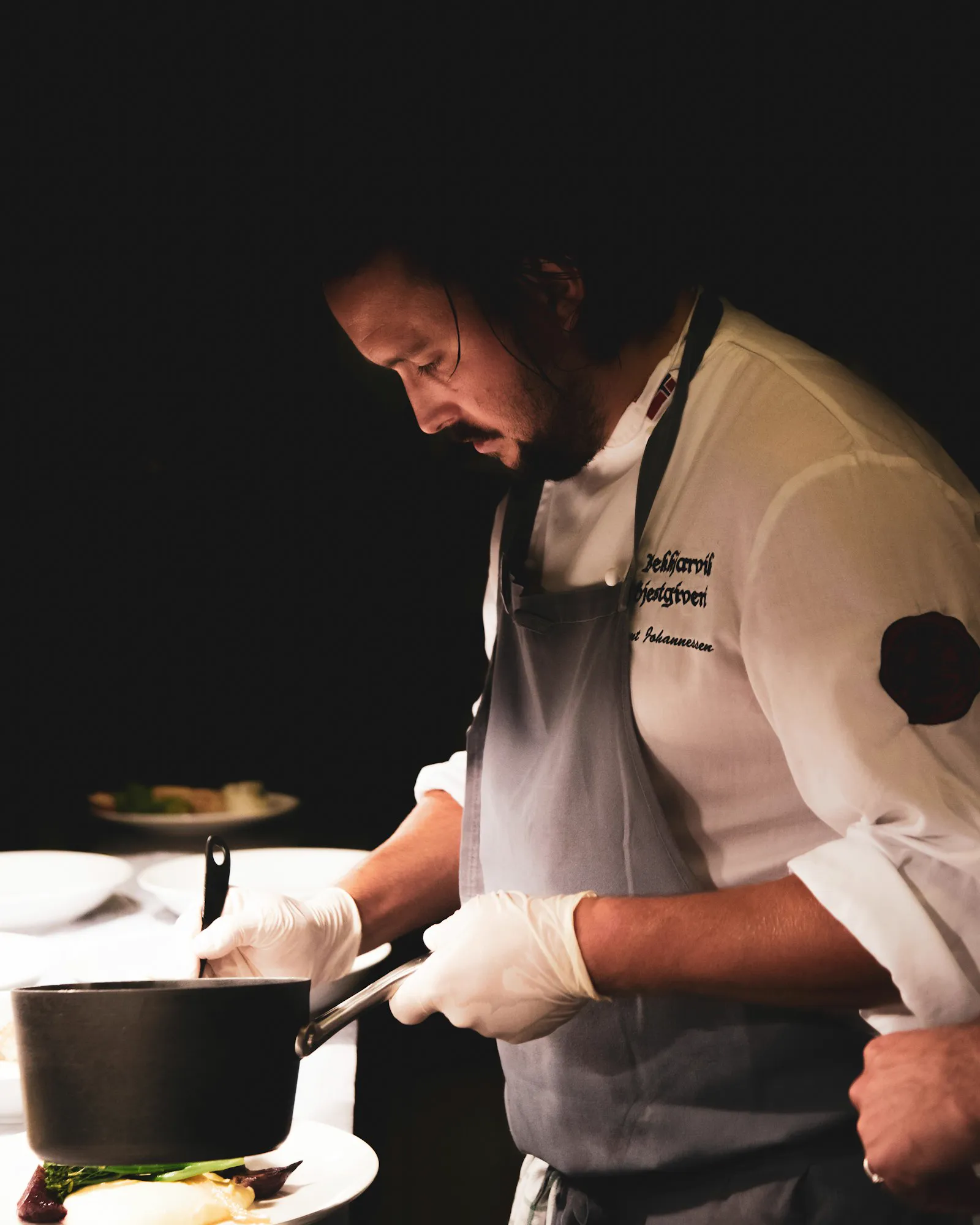 Chef emplatando en una cocina con luz baja